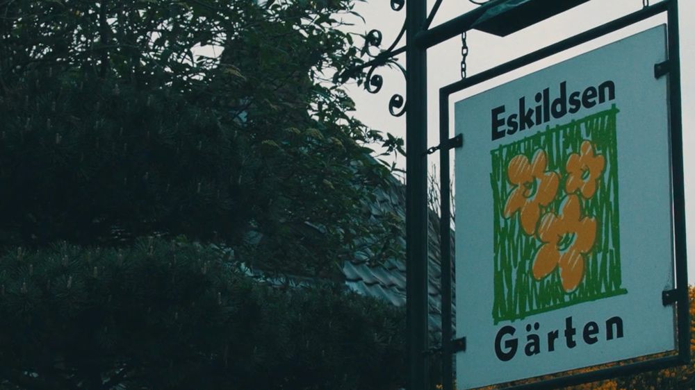 Historisches Firmenschild von Eskildsen Gärten vor grünen Bäumen