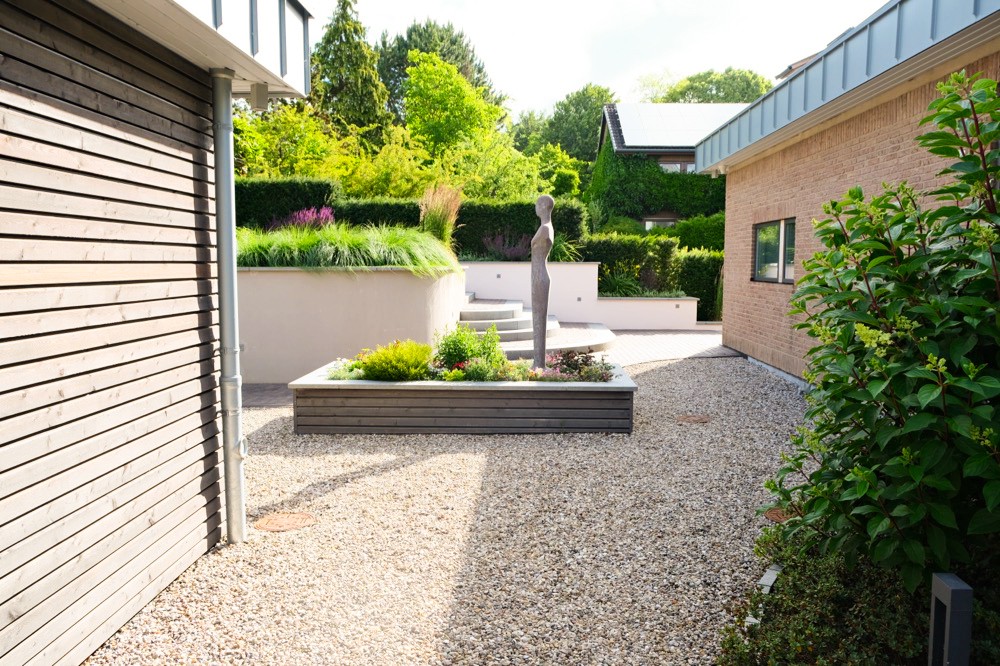 Moderner Gartenhof mit Kiesfläche, Hochbeet und Solitärgehölz